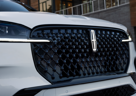 The black grille of a white 2025 Lincoln Aviator® SUV is shown with its fog lights on. | Thomasville Lincoln in Thomasville GA
