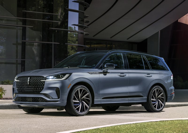 A gray 2025 Lincoln Aviator® SUV is parked outside a modern building showcasing the driver’s side of the vehicle. | Thomasville Lincoln in Thomasville GA