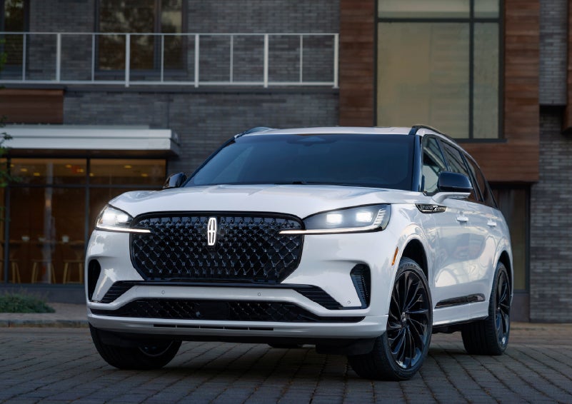 A 2026 Lincoln Aviator® Reserve model is shown with the available Jet Appearance Package parked near a restaurant. | Thomasville Lincoln in Thomasville GA